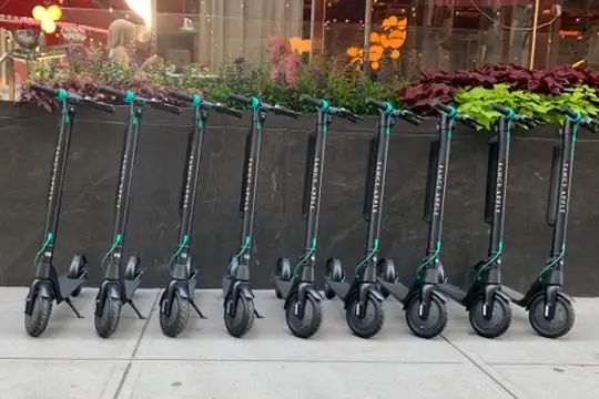 Row of black electric rental scooters ready for pickup in NYC