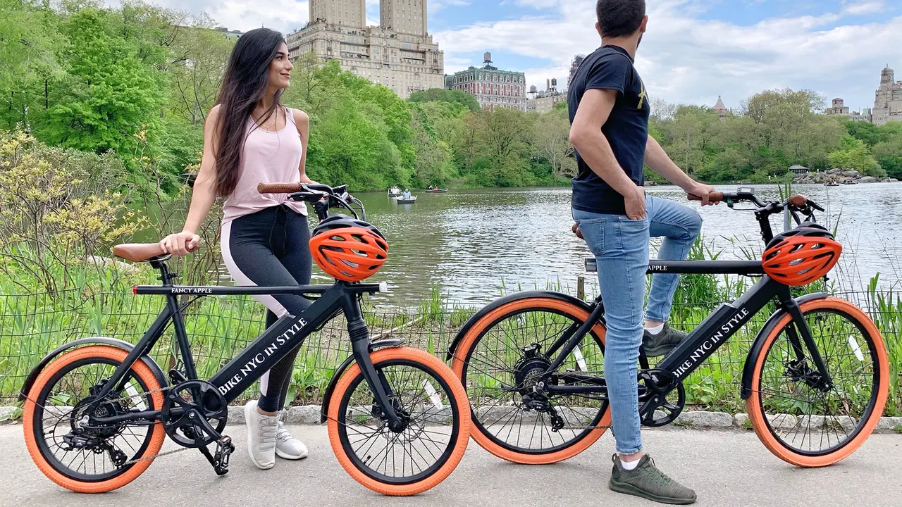 Two electric bikes with helmets parked beside the Central Park lake
